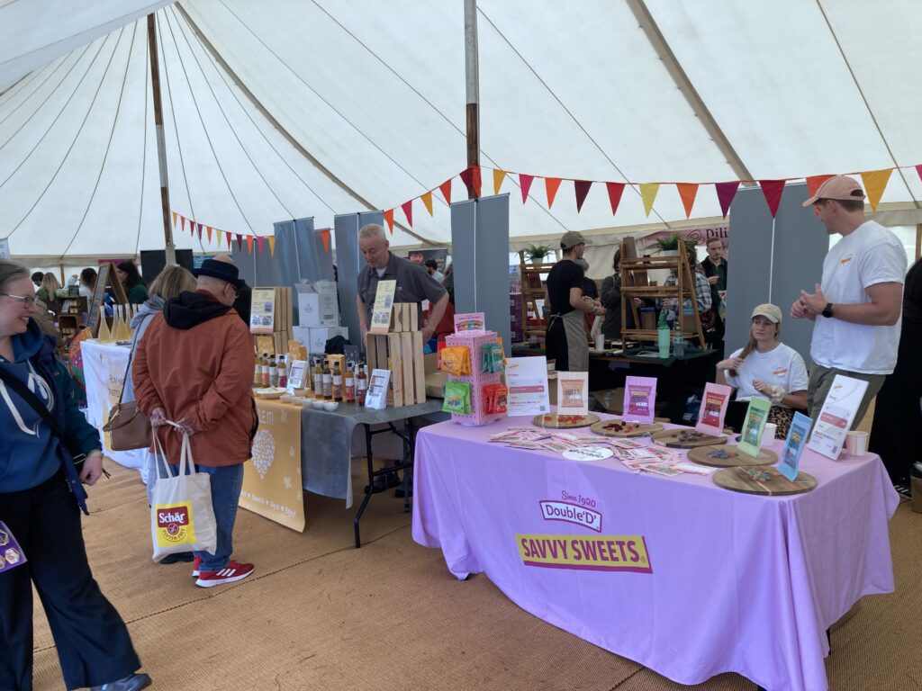Visitors browsing free-from food and drink stalls inside the marketplace tent at the Free From Festival, Birmingham